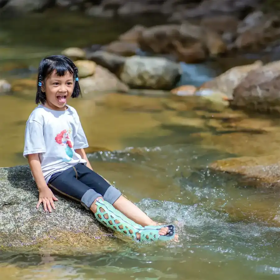 Child sitting in a stream wearing a FlexiOH short leg immobilizer