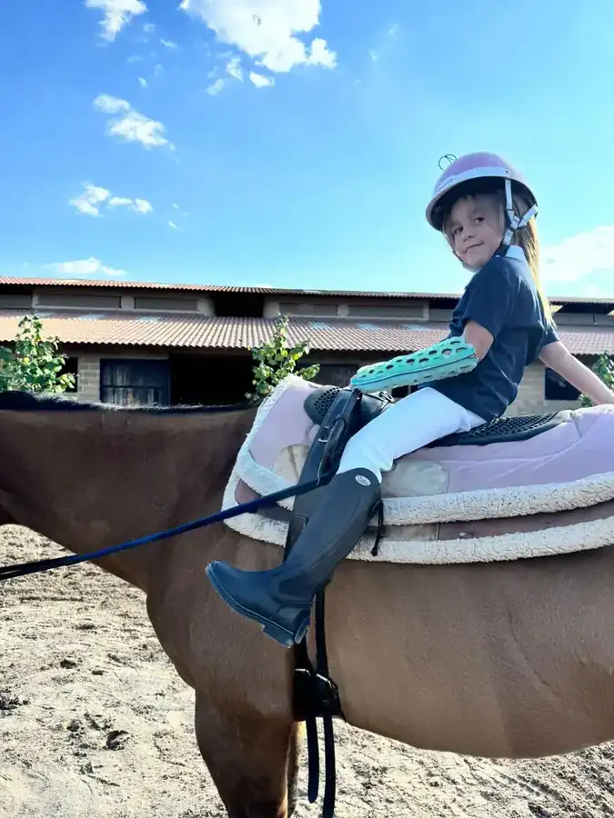 Child riding a horse wearing a FlexiOH arm immobilizer