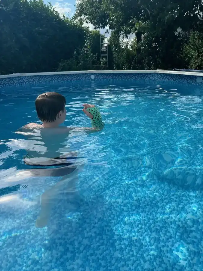 Boy swimming in a pool wearing a FlexiOH arm immobilizer